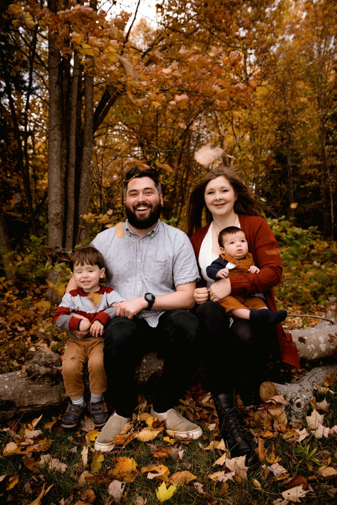 Famille assise sur un tronc dans une forêt d'automne