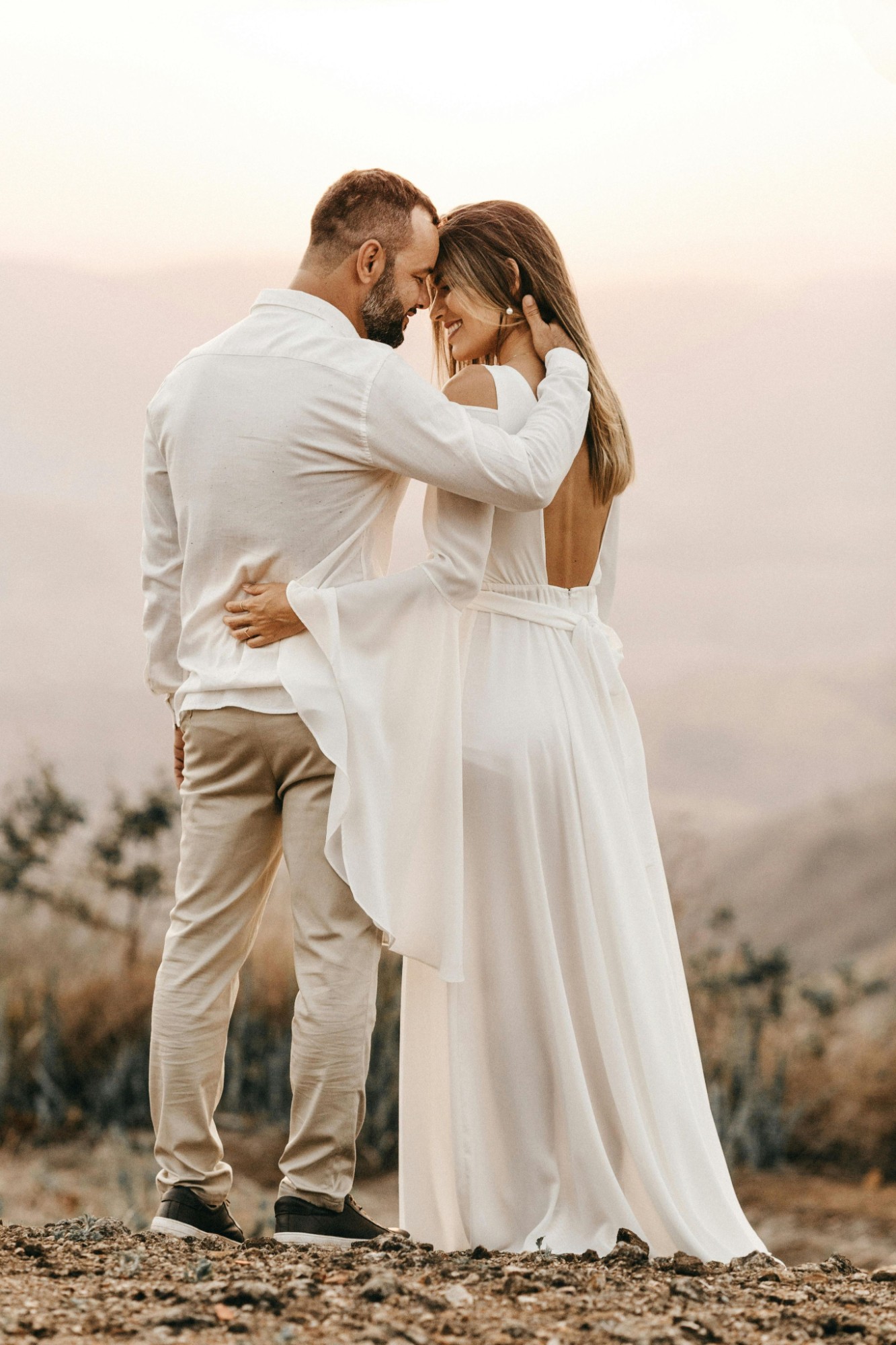 Couple de mariés tout de blanc vêtus au coucher du soleil