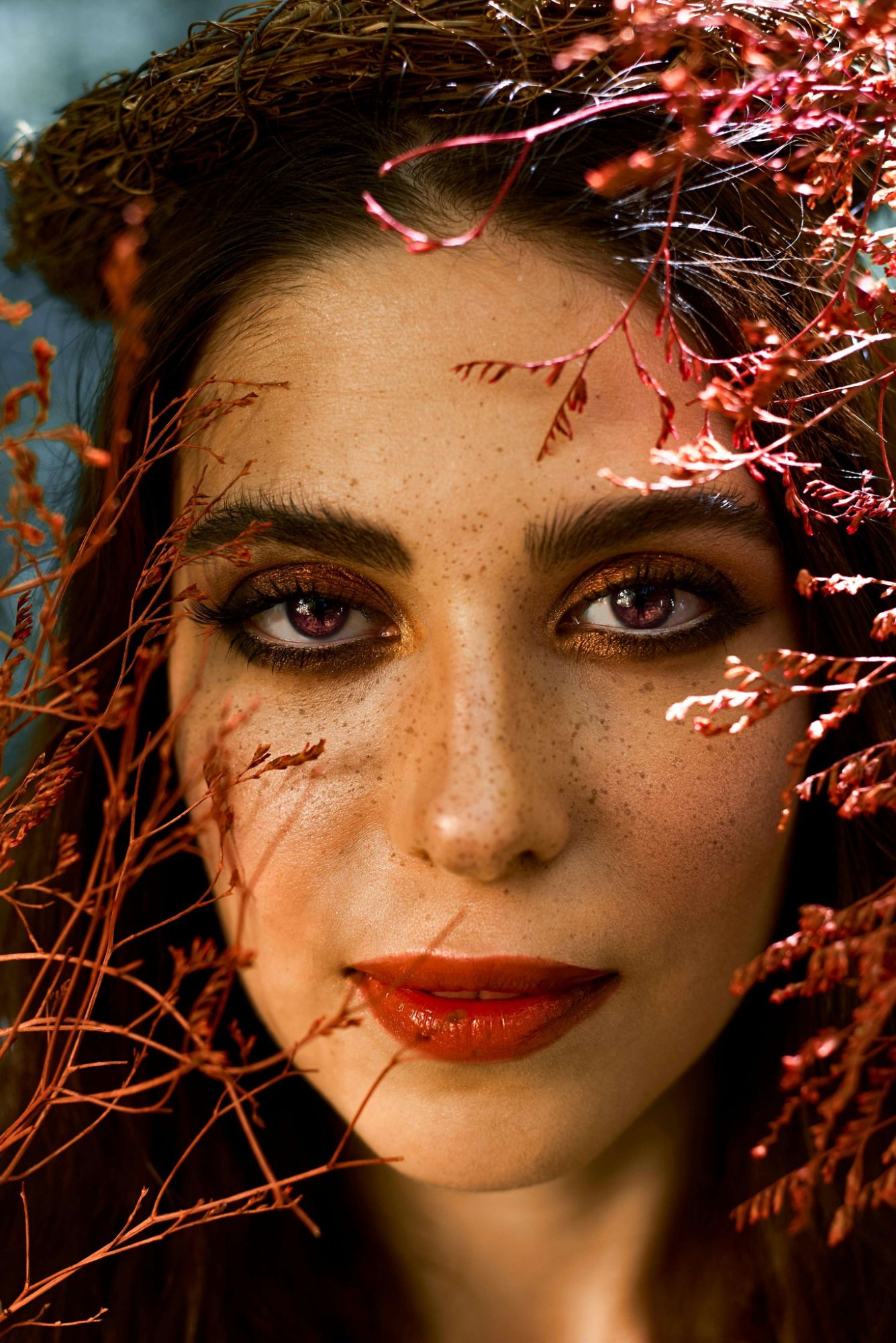 Portrait rapproché d'une femme entourée de branches cuivrées