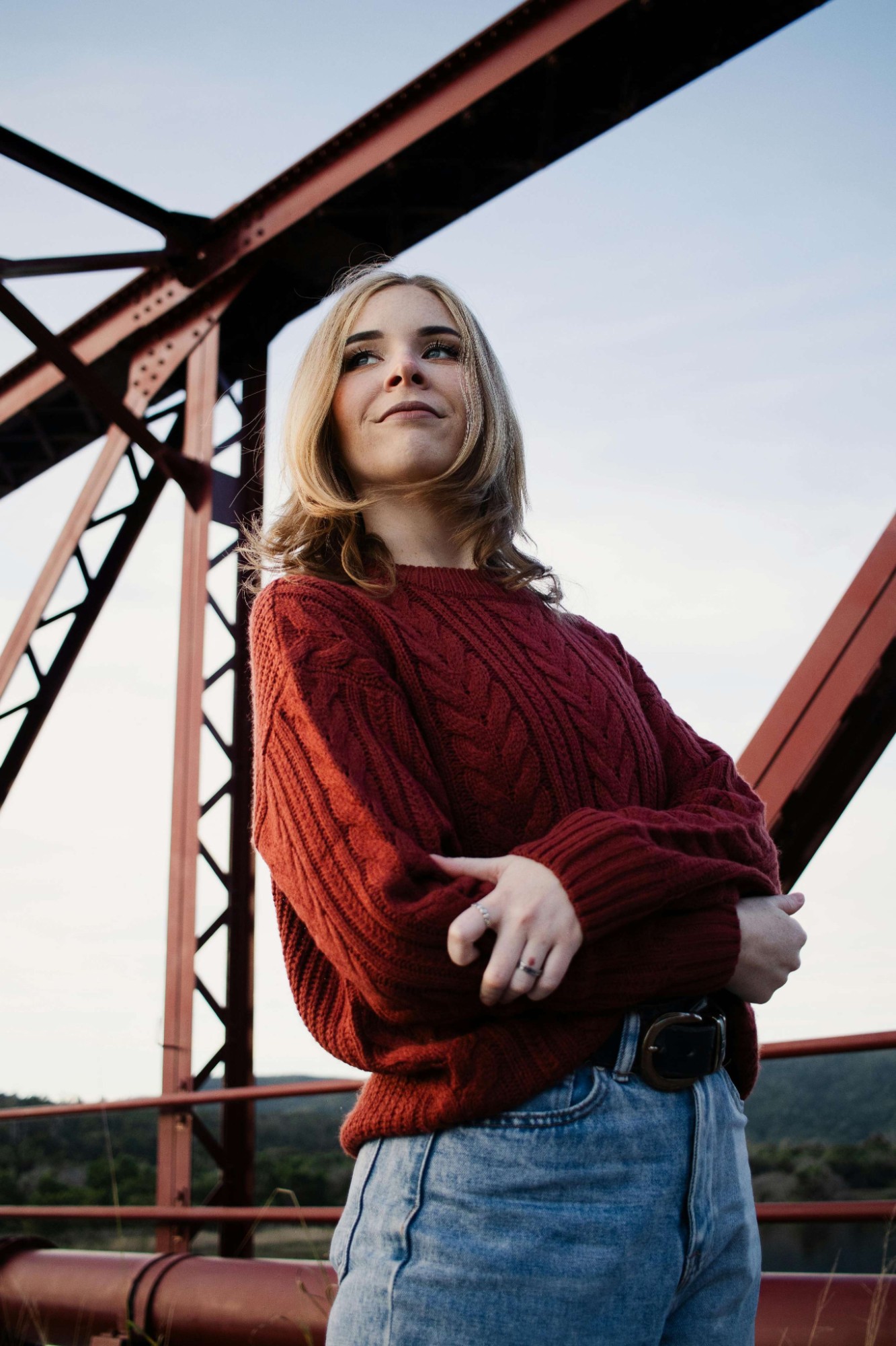 Portrait d'une femme en pull rouge sur un pont métallique
